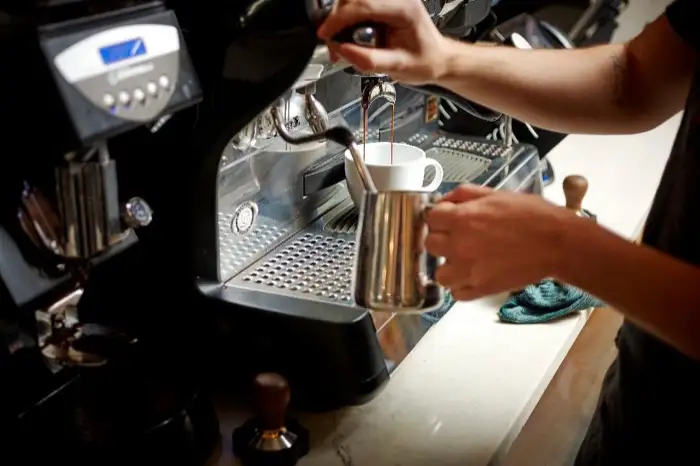 Barista steaming milk at the espresso machine