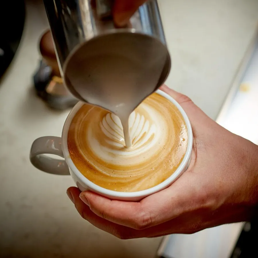 A barista pouring a latte