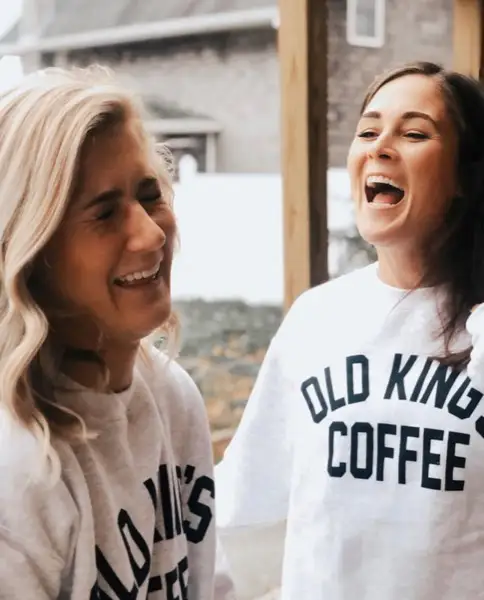 Two friends laughing in Old King's Coffee sweatshirts