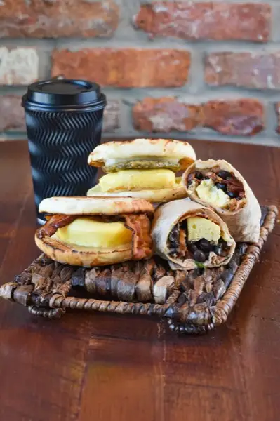 Breakfast sandwiches and wraps on a wicker tray